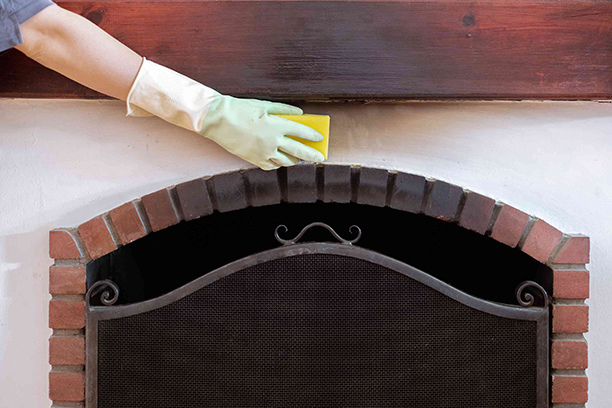 Hand Cleaning Brick Fireplace Mantel with Yellow Sponge