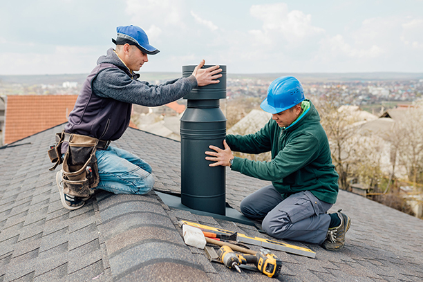 Two Workers Installing Chimney on Rooftop as Part of Fireplace Chimney Repair