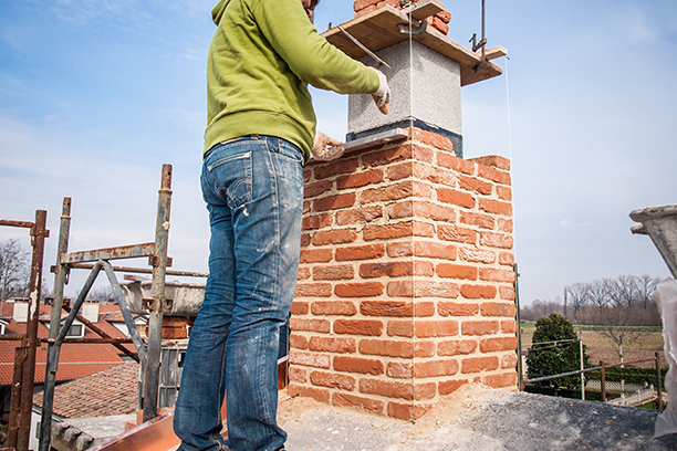 Worker Repairing Brick Chimney on Roof in Warwick RI