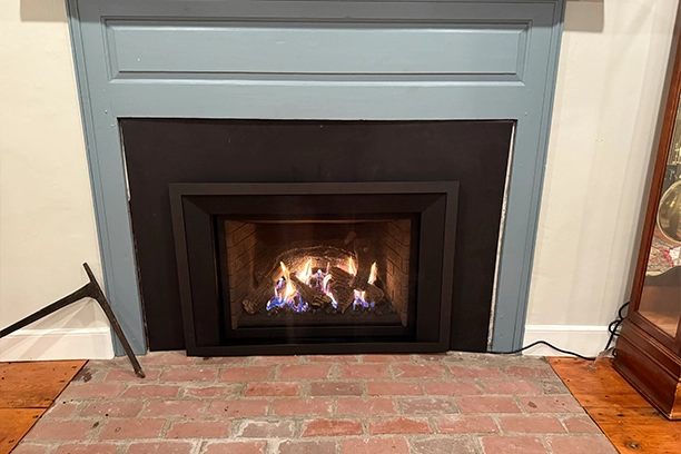 Modern Fireplace Insert With Burning Logs and Brick Hearth