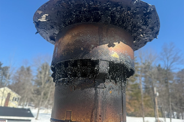 Rusty Chimney Stack with Creosote Buildup Under Clear Blue Sky