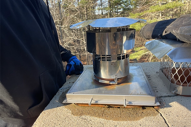 Worker Installing Metal Chimney Cap During Fireplace Chimney Repair Warwick RI